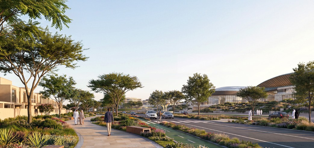 The landscaped spine at Wadeem Gardens: a walking path, a cycle lane and a road running past villas towards the arena
