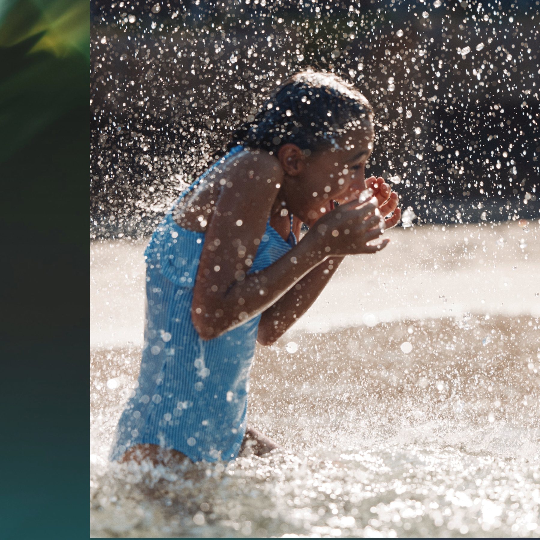 A child under a splash pad at Yas Riva Reserve